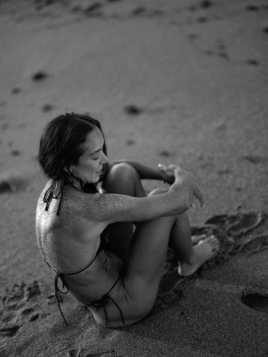 Female fitness athlete photographed on volcanic dark sand in Marbella
