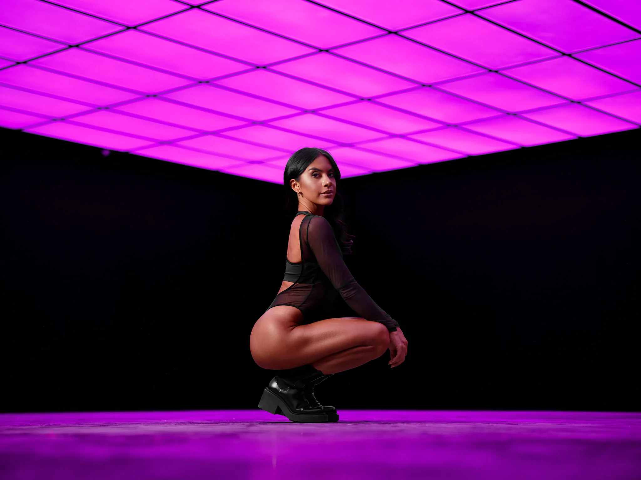 The Neon at Story + Space Nottingham with the RGB ceiling in magenta, fitness coach Jasmine Dawn crouched under the light