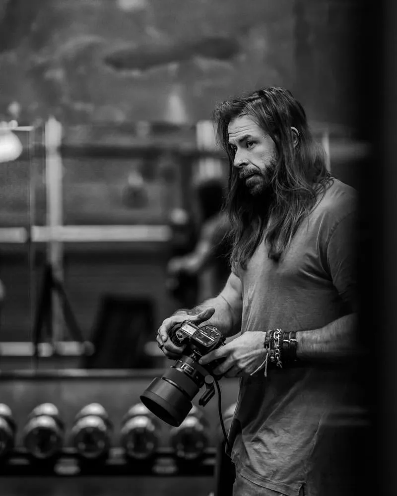 Christopher Bailey in his gym studio holding camera - black and white
